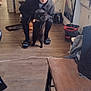person, cat, indoor, kitchen, floor, chair, slippers, hoodie, black_cat, wooden_floor, household_items, appliance, mop, bucket, young_person, furniture, casual, pet, curly_hair, looking_at_camera