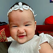Luna Rose is registered to the contest to win money with this photo: baby, child, chubby_cheeks, closeup, couch, cute, decor, fabric, face, frill, happy, headband, home, indoor, infant, person, pillow, portrait, smiling, white_clothing