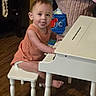 child, colorful_background, cute, floor, furniture, home, indoor, musical_instrument, orange_clothing, person, piano, playful, seat, smiling, stool, toddler, tongue_out, toy, wooden_floor, young_child