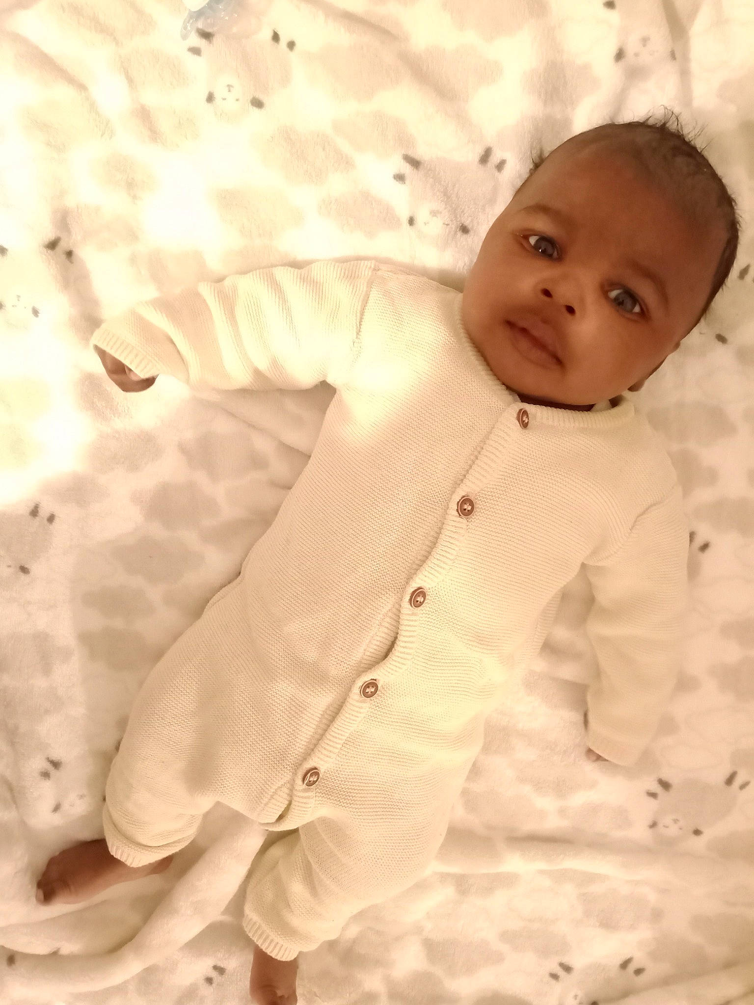 Nofy participe au concours pour gagner de l'argent avec cette photo : baby, baby_toddler_clothing, bedding, child, collar, comfort, dress_shirt, flooring, happy, linens, nose, outerwear, pattern, person, sitting, sleeve, smile, suit, textile, toddler