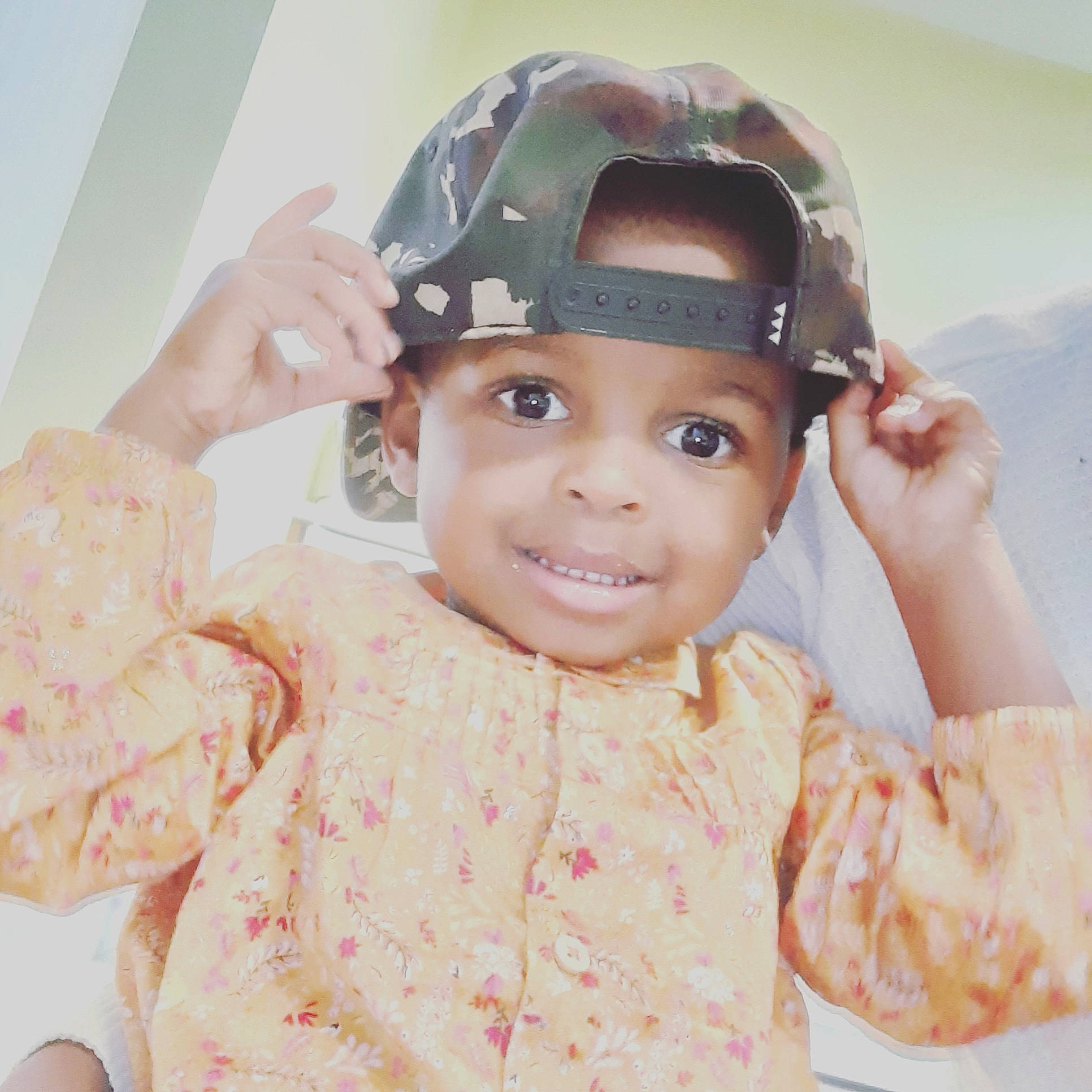 Tahia participe au concours pour gagner de l'argent avec cette photo : baby, cap, child, fashion_accessory, forehead, fun, gesture, head, headgear, joy, person, personal_protective_equipment, toddler