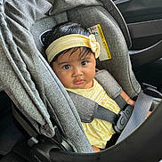 Itzel is registered to the contest to win money with this photo: baby, child, car_seat, headband, yellow_clothing, seatbelt, car_interior, portrait, infant, cute, child_seat, safety, car, person, young_child, indoors, seat, straps, face, looking