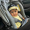 baby, child, car_seat, headband, yellow_clothing, seatbelt, car_interior, portrait, infant, cute, child_seat, safety, car, person, young_child, indoors, seat, straps, face, looking