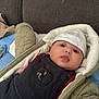 Naseem a rejoint le concours — aidez-le/la à gagner de superbes lots ! baby, infant, face, hat, clothing, overalls, jacket, couch, blanket, indoor, cute, child, portrait, warm, cozy, smile, person, headwear, soft, young