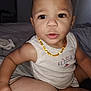 toddler, child, baby, necklace, sleeveless_shirt, bed, person, hand, face, indoor, curious, looking, skin, furniture, clothing, young_child, expression, holding, closeup, casual