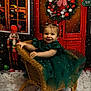 background, celebration, child, christmas, cute, decorations, festive, girl, green_dress, happy, holiday, indoor, nutcracker, person, portrait, smiling, snow, toddler, wicker_chair, wreath