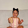Jade is registered to the contest to win money with this photo: baby, child, smiling, sitting, romper, headband, bow, toy, wooden_toy, couch, white_couch, indoor, cute, happy, infant, barefoot, person, portrait, skin, furniture