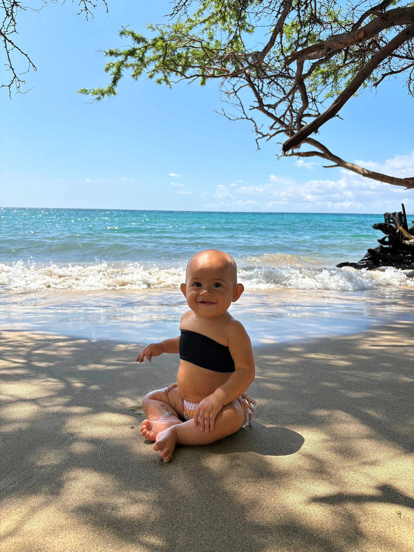 Jade joined the competition — help win amazing prizes! baby, child, beach, sand, ocean, water, waves, sunlight, shadow, tree_branch, smile, sitting, nature, outdoor, toddler, summer, vacation, happy, barefoot, sky