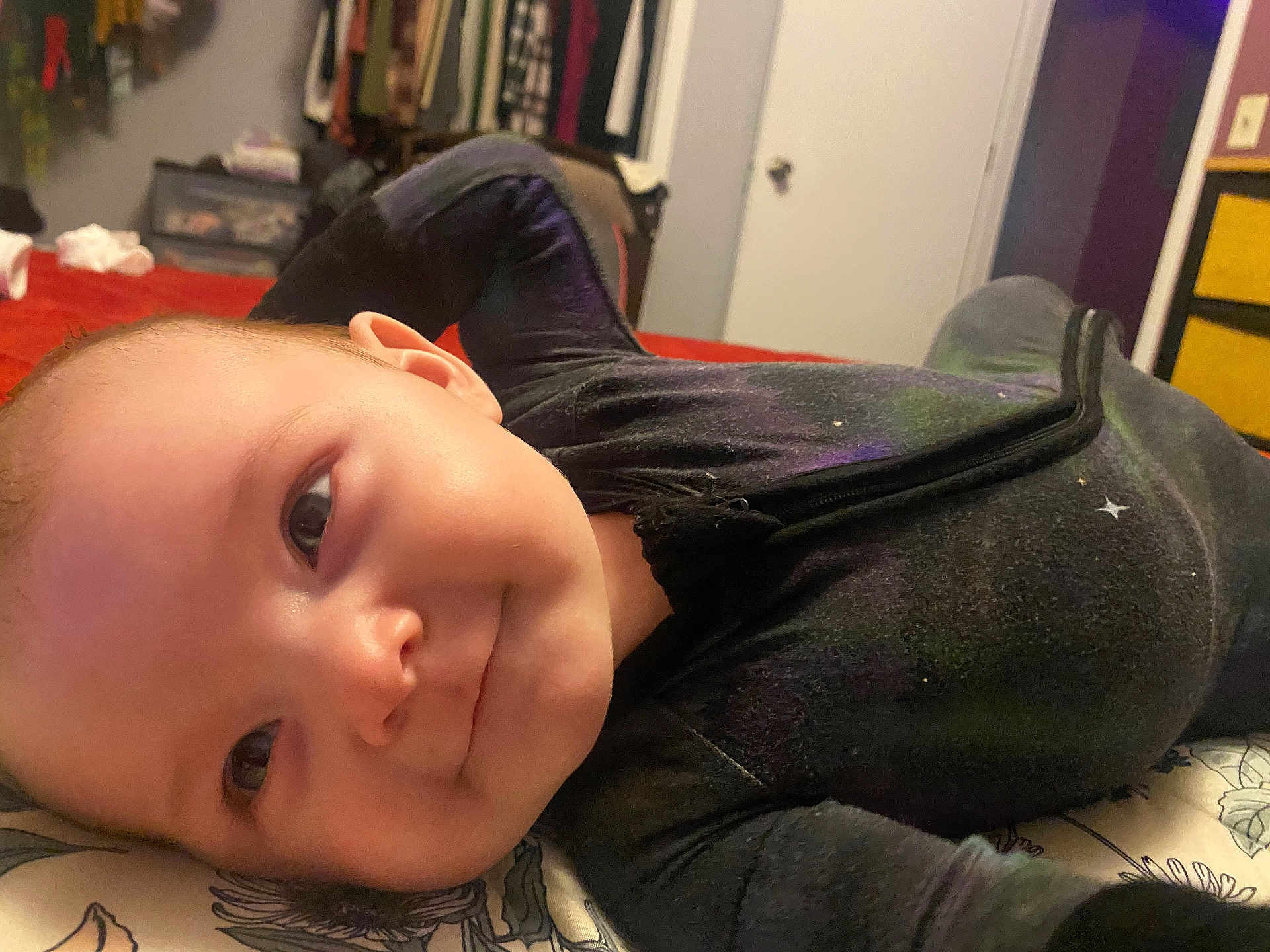 Defiance is registered to the contest to win money with this photo: baby, smiling, face, indoors, bed, clothing, infant, person, portrait, child, cute, lying_down, happy, room, furniture, blanket, sleepwear, head, young, cozy