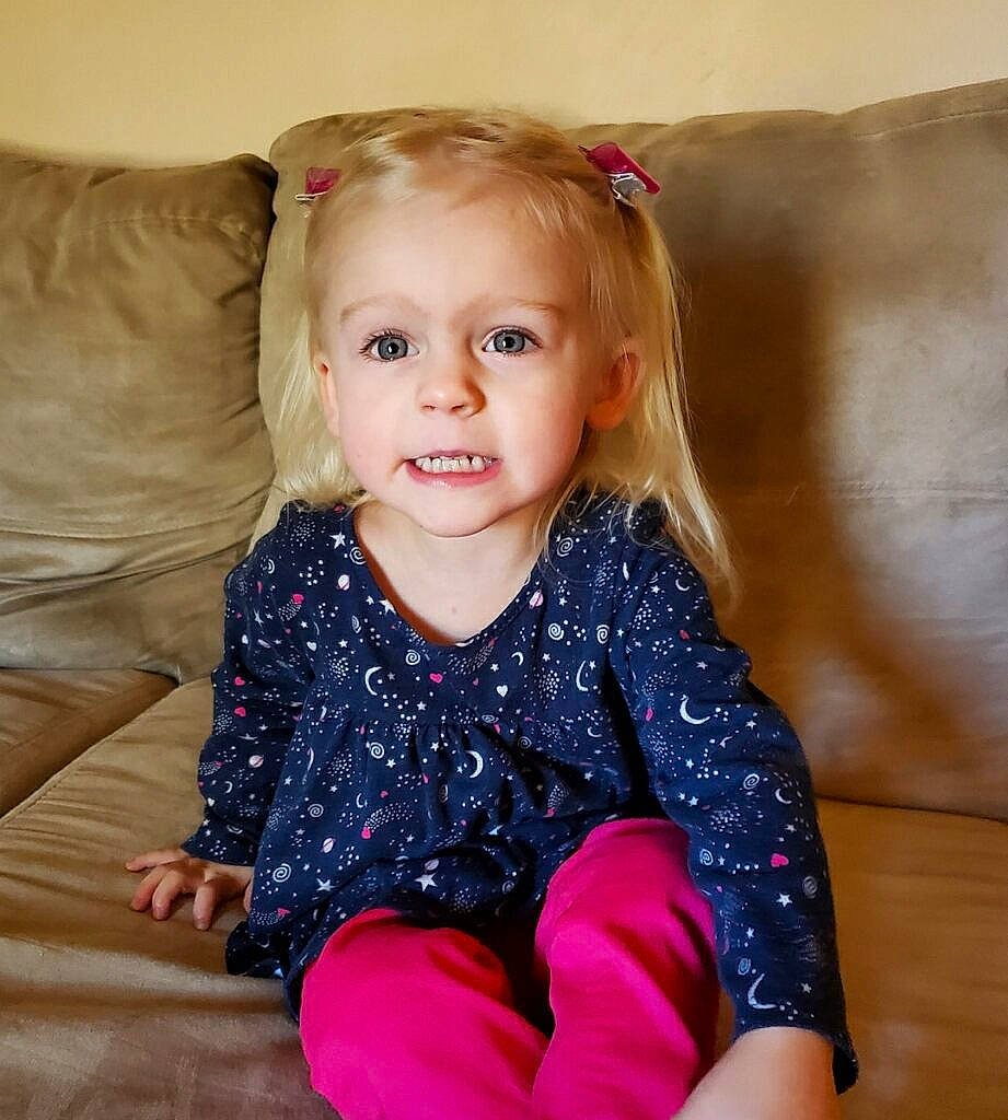 Arizona is registered to the contest to win money with this photo: arm, baby_toddler_clothing, cheek, dress, eye, face, flash_photography, hair, happy, head, human_body, iris, leg, neck, person, pink, product, skin, sleeve, smile