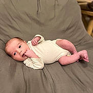 Charly participe au concours pour gagner de l'argent avec cette photo : baby, infant, cushion, chair, indoor, cute, lying_down, onesie, hand, face, skin, newborn, curious, comfort, relaxation, small, child, person, soft, resting