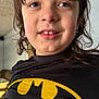 child, face, smile, batman_logo, shirt, black_clothing, curly_hair, indoor, portrait, closeup, happy, casual, person, youth, light, expression, cute, young, toddler, playful