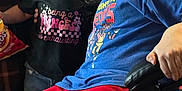 Braxton is registered to the contest to win money with this photo: child, children, glasses, pink_glasses, black_shirt, blue_shirt, red_pants, indoor, chair, snack, chips, smile, happy, portrait, person, casual_clothing, hair, friendship, toddler, candid