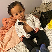 Elias joined the competition — help win amazing prizes! toddler, child, bed, blanket, clothing, socks, indoor, person, curly_hair, portrait, expression, white_shirt, bow_tie, pants, casual, furniture, home, young_child, sitting, face