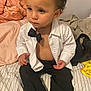 Elias is registered to the contest to win money with this photo: toddler, child, boy, indoor, bed, blanket, clothing, shirt, bow_tie, pants, socks, furniture, person, portrait, cute, expression, curly_hair, seated, casual, home