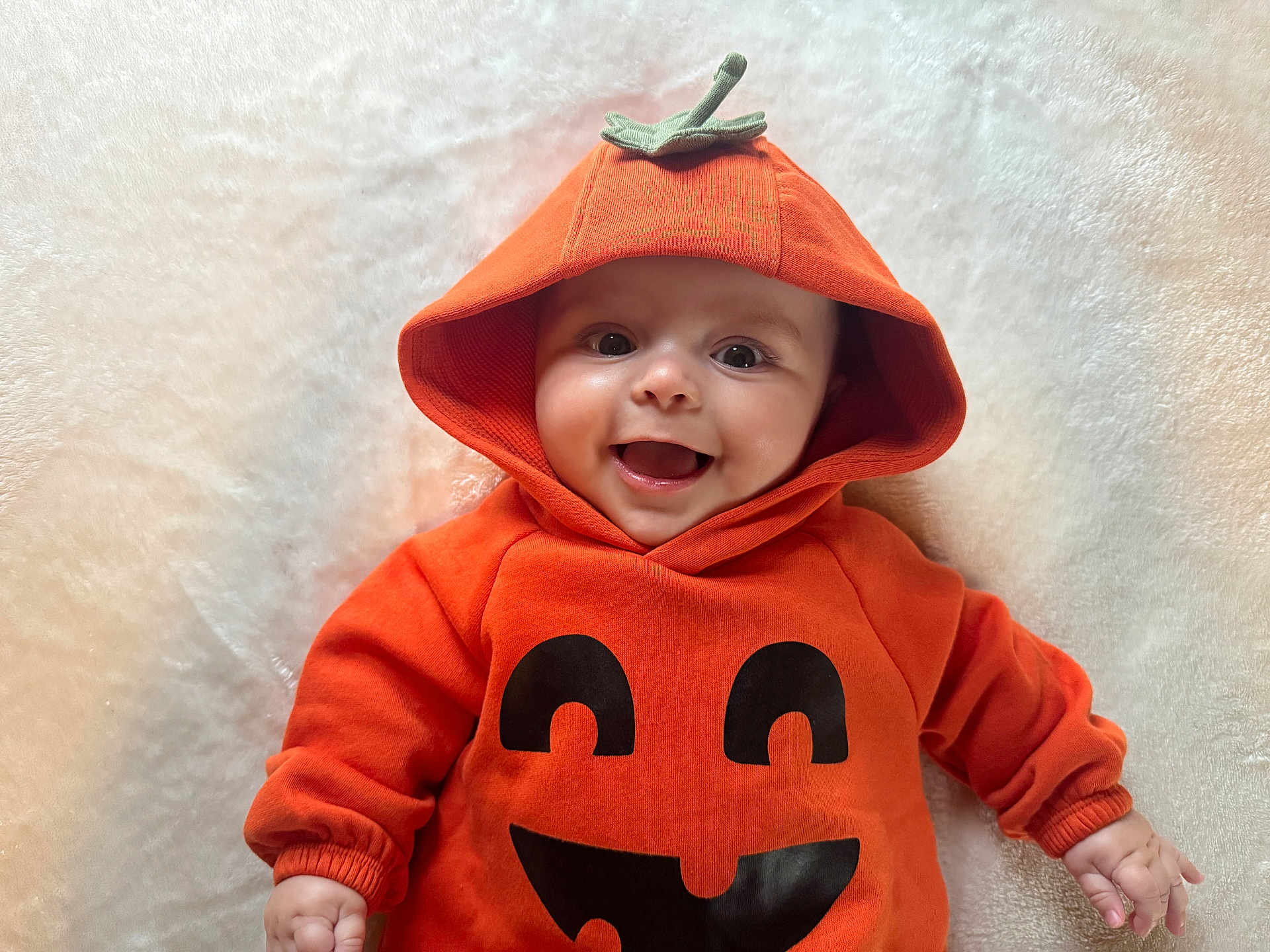 Gabriel joined the competition — help win amazing prizes! baby, child, hoodie, orange, pumpkin, smile, happy, cute, infant, face, clothing, costume, hood, lying_down, white_background, soft_texture, hands, eyes, joyful, portrait