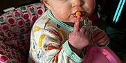 Penelope is registered to the contest to win money with this photo: baby, bib, bodypart, couch, cream, cutlery, dessert, eating, face, finger, food, furniture, hand, head, icing, ketchup, person, photography, portrait, spoon
