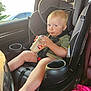 toddler, child, car_seat, drink, dairy_queen, straw, blonde_hair, car_interior, seatbelt, cup_holder, relaxed, cute, young_child, sitting, window, sunlight, car_door, foot, green_shirt, pink_blanket