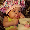 Khalani is registered to the contest to win money with this photo: baby, infant, child, portrait, bottle, feeding, party_hat, pink, yellow, clothing, blanket, plush, sitting, indoors, close_up, face, eyes, hand, cozy, patterned_background