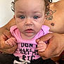 Zella is registered to the contest to win money with this photo: baby, child, person, adult_hands, curly_hair, blue_eyes, pink_shirt, tattoo, holding_hands, close_up, indoor, casual_clothing, expression, portrait, skin, face, infant, young_child, candid, human