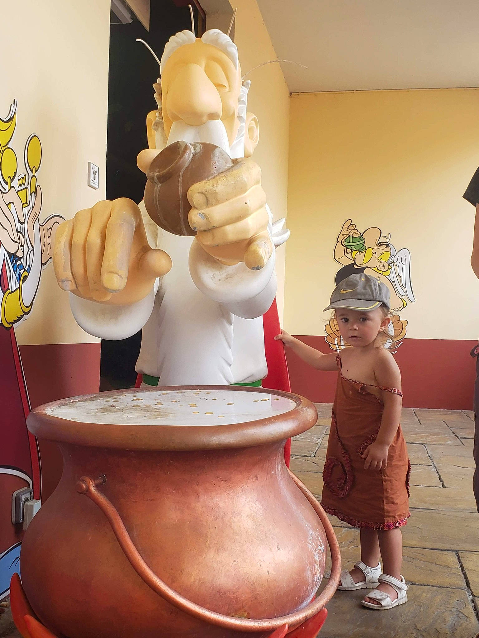 Lilou participe au concours pour gagner de l'argent avec cette photo : art, carving, ceramic, flooring, hat, headwear, interior_design, leisure, organ, person, porcelain, pottery, room, sandal, sculpture, serveware, shorts, statue, sun_hat, toddler