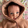 baby, child, face, blue_eyes, hood, bear_ears, cozy, blanket, floral_pattern, cute, portrait, infant, soft_texture, clothing, warm, lying_down, closeup, skin, expression, adorable