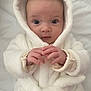 baby, infant, hooded_robe, white_clothing, soft_texture, hands, face, eyes, cute, cozy, portrait, newborn, child, warm_clothing, indoor, skin, expression, person, laying_down, blanket
