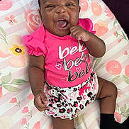 Kiari joined the competition — help win amazing prizes! baby, infant, smiling, happy, pink_clothing, patterned_shorts, cushion, floral_pattern, cute, child, portrait, indoors, lying_down, black_socks, cheerful, expression, young, person, skin, face