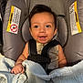 baby, car_seat, blanket, smiling, infant, child, straps, seatbelt, clothing, happy, face, indoors, person, cute, young_child, baby_girl, baby_boy, comfort, security, portrait