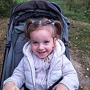 Iris a rejoint le concours — aidez-le/la à gagner de superbes lots ! child, toddler, stroller, outdoor, smiling, pigtails, vest, sweater, nature, path, grass, trees, happy, person, baby, autumn, park, playful, cute, portrait