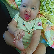 Penelope is registered to the contest to win money with this photo: baby, child, smiling, happy, onesie, foot, hand, quilt, blanket, blue_eyes, cute, sitting, indoors, infant, person, playful, skin, young_child, expression, holding