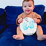 Penelope is registered to the contest to win money with this photo: baby, child, smile, blue_couch, handmade_card, handprints, fathers_day, happy, sitting, indoors, cute, person, foot, shirt, infant, celebration, gift, portrait, home, love