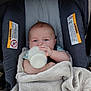 baby, infant, car_seat, blanket, bottle, milk, cute, child, blue_eyes, soft, cozy, indoors, clothing, feeding, person, baby_hair, seat, comfort, rest, portrait