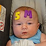 Jax is registered to the contest to win money with this photo: baby, infant, face, drool, foam_letters, blue_clothing, car_seat, child, cute, expression, indoor, head, skin, person, seat, soft_toys, plush, resting, young, closeup