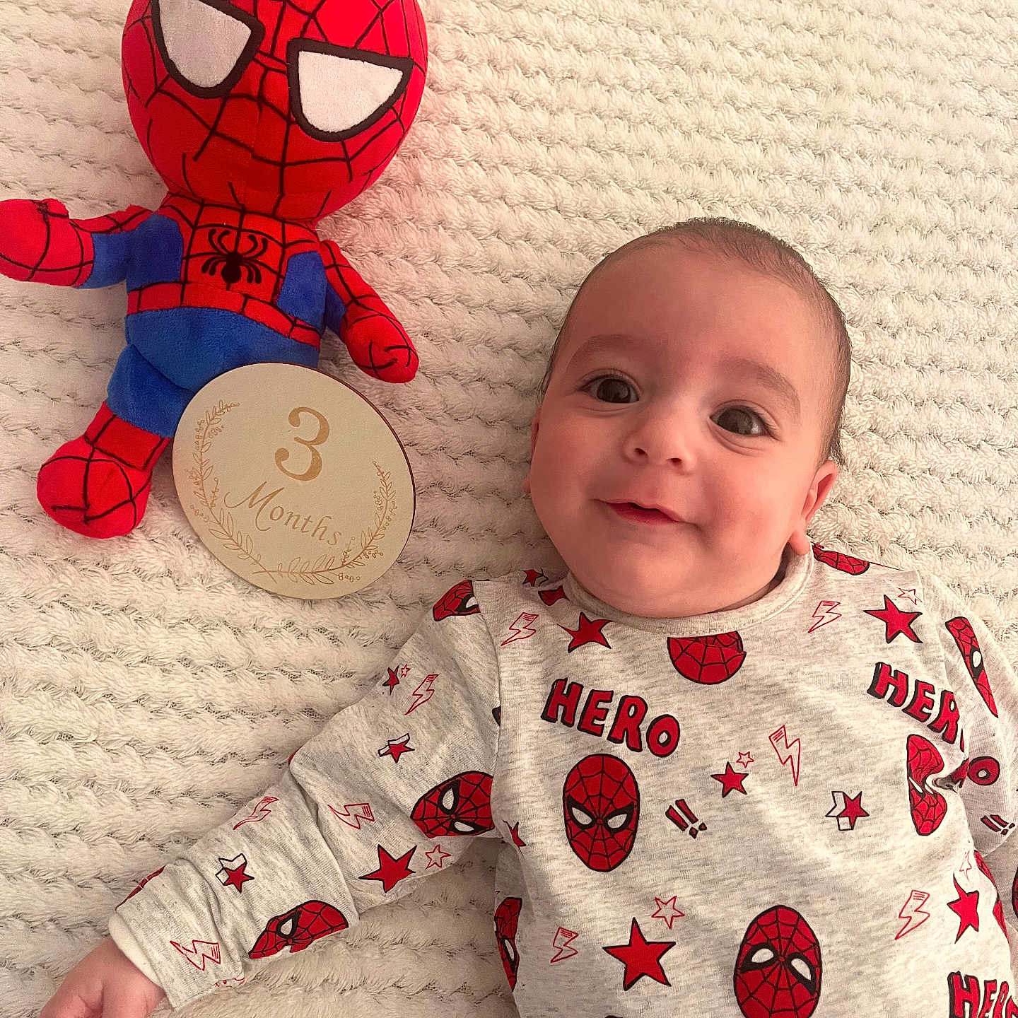 Pablo a rejoint le concours — aidez-le/la à gagner de superbes lots ! baby, infant, smile, face, plush_toy, spider_man, milestone_card, blanket, patterned_clothing, red, blue, cream, cute, lying_down, child, portrait, soft_toy, happy, young_child, indoor
