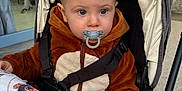 Liam a rejoint le concours — aidez-le/la à gagner de superbes lots ! baby, child, clothing, curtain, fabric, face, hair, hand, hoodie, jacket, monkey_print, outdoor, pacifier, person, pillow, seatbelt, sidewalk, stroller, toddler, window