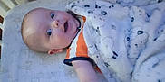 Thomas joined the competition — help win amazing prizes! baby, infant, crib, blanket, bed, sleeping_area, orange_clothing, white_blanket, patterned_blanket, blue_eyes, surprised_expression, cute, child, indoor, soft_texture, person, lying_down, toddler, head, face