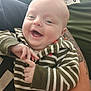 Thomas joined the competition — help win amazing prizes! baby, smiling, striped_clothing, hoodie, hands, tattoo, adult_arm, holding, happy, face, infant, person, closeup, portrait, cute, joyful, child, casual_wear, indoor, human