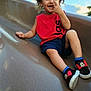 Arz is registered to the contest to win money with this photo: child, toddler, curly_hair, red_shirt, blue_shorts, mickey_mouse_shoes, slide, playground, smiling, laughing, outdoor, sky, sunlight, cute, happy, fun, play, casual_clothing, bare_arms, feet