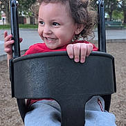 Arz joined the competition — help win amazing prizes! toddler, child, swing, playground, curly_hair, smile, happy, outdoor, park, red_shirt, gray_pants, hand, face, play, fun, daytime, nature, trees, seat, metal_chains