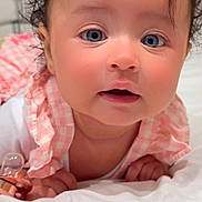 Marília joined the competition — help win amazing prizes! baby, infant, face, blue_eyes, curly_hair, bow, pink_clothing, pacifier, blanket, white, cute, toddler, portrait, closeup, child, skin, hand, expression, indoors, soft