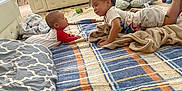 Aahil is registered to the contest to win money with this photo: toddler, baby, child, play, rug, blanket, cushion, sofa, living_room, curtain, toy, floor, indoor, smile, face, clothing, person, interaction, cozy, home