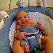 Aahil is registered to the contest to win money with this photo: baby, smile, infant, baby_seat, orange_clothing, blue_cushion, plush_toys, indoor, child, safety_harness, happy, person, young_child, seat, toy, comfort, infant_clothing, baby_accessory, portrait, relaxing