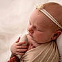 baby, sleeping, infant, headband, soft_toy, wrapped, blanket, closeup, portrait, peaceful, cute, newborn, child, hand, face, skin, resting, indoors, soft_light, cozy