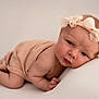 baby, infant, newborn, headband, bow, blanket, soft_texture, skin, portrait, cute, pose, cushion, resting, closeup, expression, child, peaceful, indoor, light, adorable