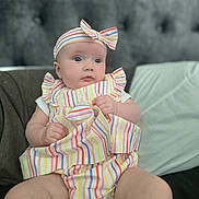 Ellise is registered to the contest to win money with this photo: baby, infant, child, striped_clothing, headband, blue_eyes, chubby_legs, sitting, indoor, cushion, blanket, soft_furniture, portrait, cute, curious, colorful, fashion, toddler, comfortable, plush