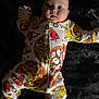 baby, infant, child, onesie, pizza_print, pajamas, lying_down, face, eyes, chubby_cheeks, portrait, cute, hand, leg, bed, blanket, dark_background, soft_light, expression, sleepwear