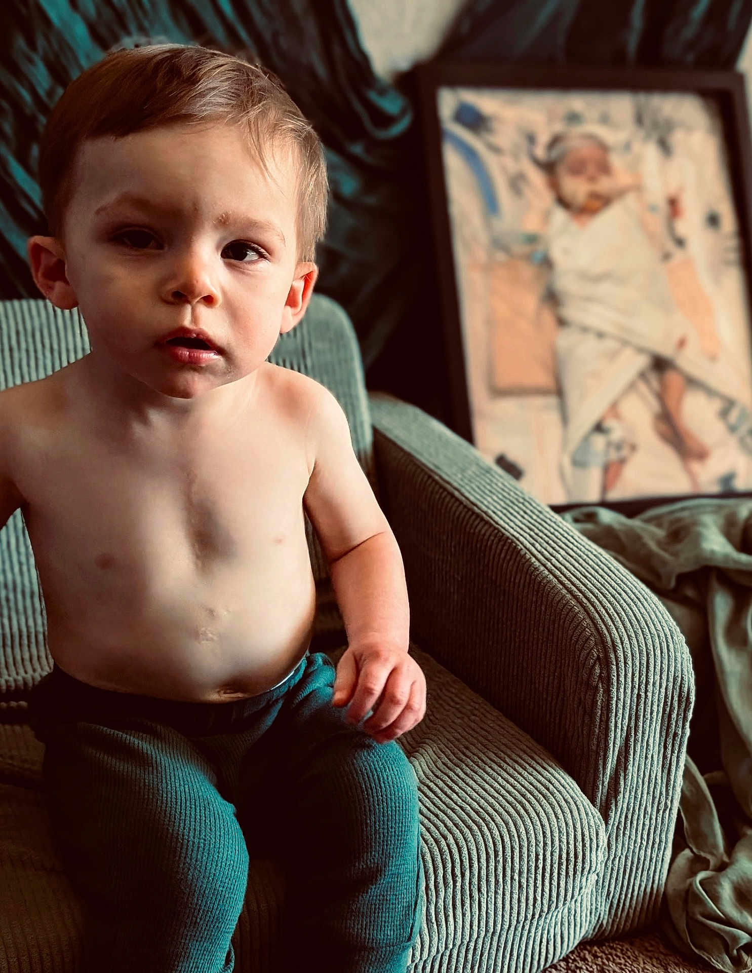 Arison is registered to the contest to win money with this photo: toddler, child, boy, shirtless, indoor, armchair, green, seated, portrait, expression, curious, painting, frame, blanket, baby, furniture, cozy, home, carpet, casual