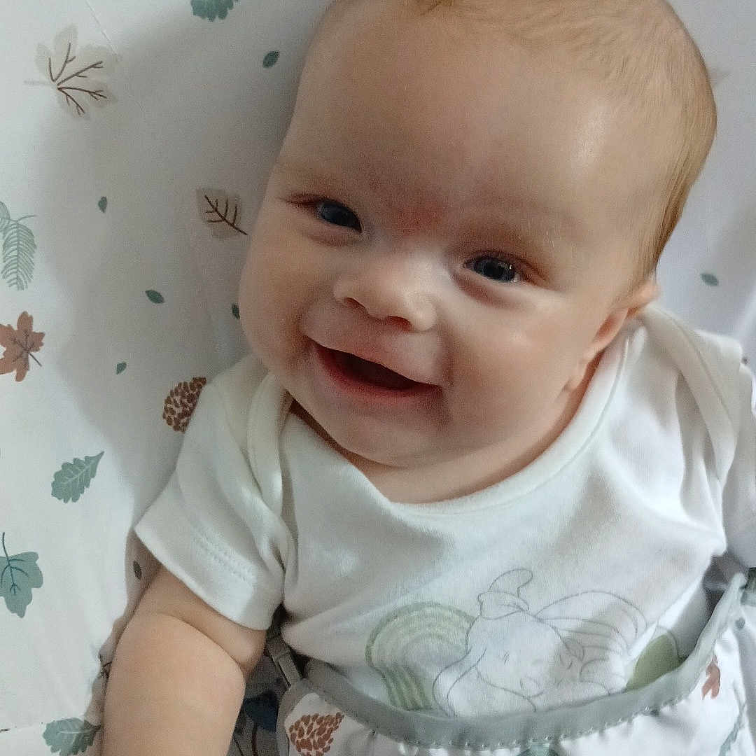 Abbie Jo joined the competition — help win amazing prizes! baby, baby_boy, cheerful, child, comfort, cushion, cute, face, happy, indoors, infant, leaf_pattern, light_skin, onesie, playful, portrait, sitting, small_hand, smiling, white_clothing