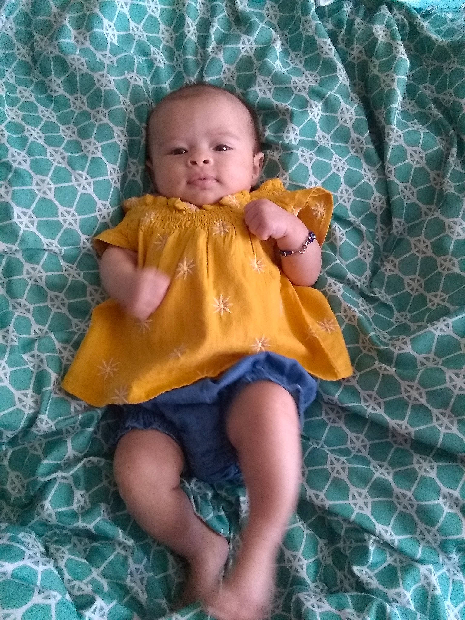 Layla is registered to the contest to win money with this photo: aqua, baby, baby_toddler_clothing, blond, child, dress, fawn, fun, head, iris, leaf, linens, mammal, pattern, person, pink, purple, sitting, skin, textile